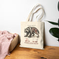 Natural Wolverine Study Tote on a wooden bench beside a plant and blanket | color:Natural
